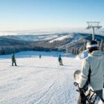 Osoba z deską snowboardową na łagodnym, przygotowanym stoku w polskich górach.