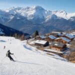 Francuski ośrodek narciarski w Alpach w słoneczny dzień, z trasą, chaletami i narciarzami w oddali