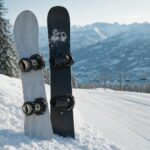 Dwie deski snowboardowe stojące w śniegu przy stoku, w tle rozmyty górski krajobraz.