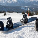Deska snowboardowa z wiązaniami i butami na śniegu przy łagodnym stoku.