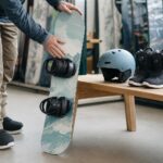 Dziecięcy snowboard, buty i kask w sklepie, osoba sprawdza wiązania przy zakupie