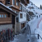 Hotel przy stoku w Szwajcarii, śnieg, wąskie dojście i narty przy wejściu