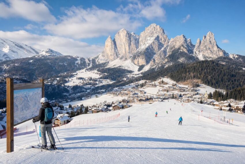Łagodny stok narciarski w Dolomitach, osoba przy mapie tras i alpejska miejscowość w tle
